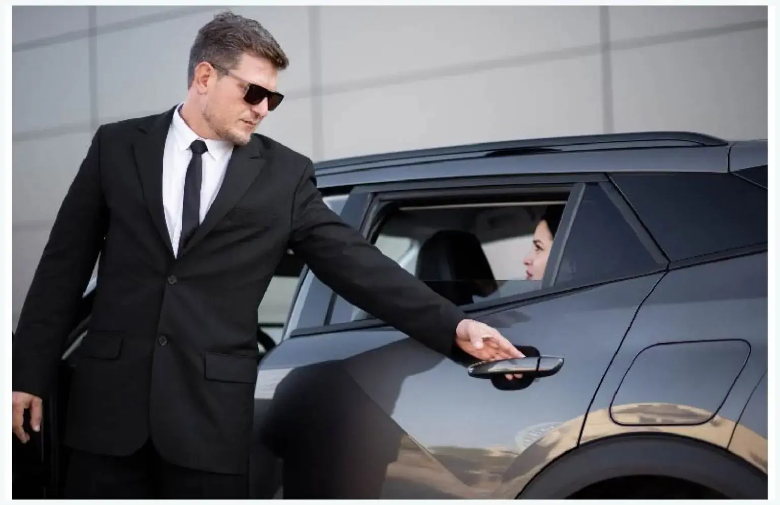 Professional chauffeur standing by luxury vehicle providing executive limo and chauffeur service